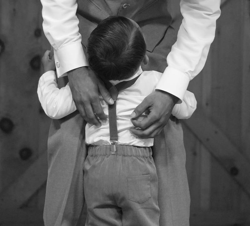 A father helping his son with his suspenders